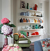 Display of glass vases and bottles on open shelving in contemporary living room