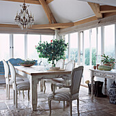 Country style dining room in light conservatory with antique dining table and chairs
