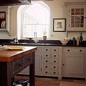 Country kitchen with arched window neutral colours cupboards and black granite worktops
