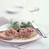 Starter of potted shrimps on sour dough toast with a salad garnish on a white plate with a knife 