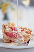 Rhabarber-Crumble mit Vanillepudding auf einem weißen Teller mit stimmungsvollem Hintergrund