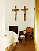 Schlafzimmer mit Stuhl und zwei Kruzifixen an der Wand
