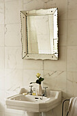 Bathroom sink with marble wall tiles and Venetian mirror