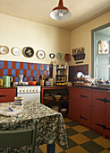 Küche mit rot gestrichenen Schränken und alten Tellern an der Wand über roten und blauen Wandfliesen