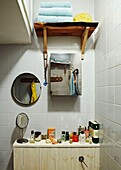 Gefliestes Badezimmer mit Metallschrank und runden Spiegeln