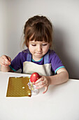 Little girl sticking gold stars on a dyed Easter Egg