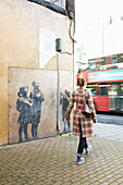 Woman walking past landmark graffiti in London city street, UK