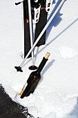 Skis and ski poles with wine bottle in snow, Zermatt, Switzerland