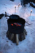 Frying pan on barbecue grill on open fire in snow, Zermatt, Valais, Switzerland