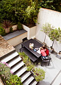 Elevated view of two girls sitting in terrace courtyard at table, London, England, UK