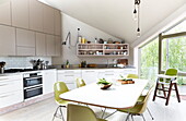 Esszimmertisch mit lindgrünen Stühlen in einer modernen offenen Küche in London, England, UK