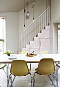 Dining room table with lime green chairs and staircase in contemporary London home, England, UK
