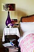 Purple lamp on bedside table with books in old London townhouse, England, UK