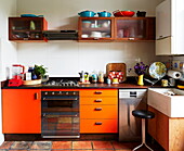Orangefarbene Retro-Einbauküche in einem farbenfrohen Haus in London, England, UK