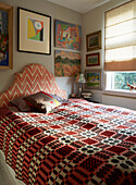 Gemusterte Decke und Kunstwerk mit Raffrollos im Schlafzimmer eines Hauses in London, England, Vereinigtes Königreich