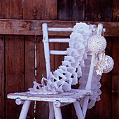 Painted wooden chair with paper chain baubles and garlands against a wooden background