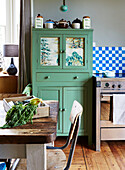 Crate of vegetables on kitchen table with green painted dresser in family home, Rye, East Sussex, England, UK