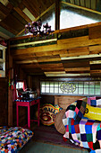 Colourful patchwork blankets and wooden ceiling in treehouse interior, East Sussex, England, UK