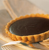 Close up of bitter sweet dark chocolate tartlet with silver fork