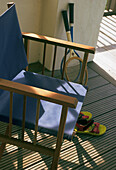 Blue director's chair with tennis rackets and sandals on wooden decking