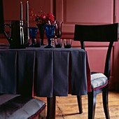 Coloured glassware on pleated tablecloth in red panelled dining room