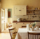 Chairs set at table in country kitchen with open door