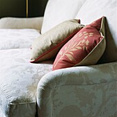 Cream coloured upholstery on sofa with red and beige floral patterned curtains