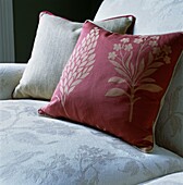 Detail of cream coloured upholstered armchair seat with floral patterned cushions