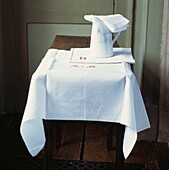 Bestickte Serviette mit Krug und weißem Tischtuch