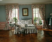 Schmiedeeisernes Bett an einem Fenster mit abgestimmten Vorhängen und Gardinen mit Blumendruck