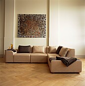 Modern artwork above light brown sofa with co-ordinated cushions and fabric
