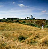 Mann wandert über Moorland zum Leuchtturm