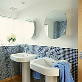 Double basins in sunlit mosaic tiled bathroom with circular mirrors