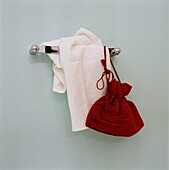 Red bag and white towel hang on bathroom wall