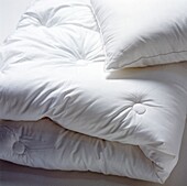 Gefaltete Bettwäsche in Nahaufnahme mit Bettdecke und Kopfkissen