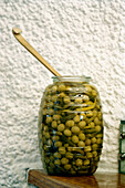 Glass jar of green olives with spoon