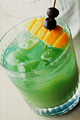 Harakiri-Cocktail aus Midori-Melonenlikör, weißem Rum und Zitronensaft, garniert mit Orangen und Blaubeeren