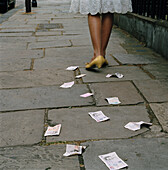 Frau beim Spazierengehen, die Geld und Kreditkarten auf der Straße fallen lässt