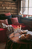 Lighted candles on solid pine trunk table in wooden chalet sitting room