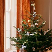 Christmas tree decorated with white bows and single stem flowers