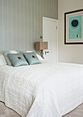 Modernes Kunstwerk in weißem Schlafzimmer mit hellgrüner Tapete und Kissen