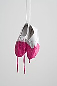 Pair of white shoes dripping with pink paint