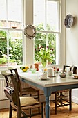 Pew chairs at painted kitchen table in window of London home   UK