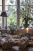 In braunes Papier eingewickelte Weihnachtsgeschenke auf dem Tisch am Fenster von Benenden cottage, Kent, England, UK