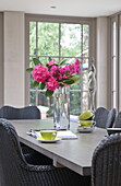 Pink flowers with lime green teacups on dining table in contemporary Haywards Heath home,  West Sussex,  England,  UK