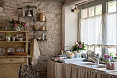 Gardinen über dem Spülbecken in der Küche eines Bauernhauses aus Stein, Dordogne, Frankreich