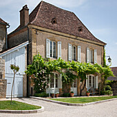 Sonnenbeschienener Außenbereich eines Landhauses in der Dordogne mit Ziegeldach und Fensterläden Frankreich