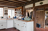 White fitted kitchen with crockery dresser and basket of books in High Halden cottage  Kent  England  UK