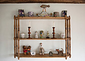 Sammlung von Ornamenten und Figuren auf einem an der Wand befestigten Holzregal in High Halden cottage Kent England UK