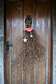 Dried flowers and Christmas stars on wooden front door of Kilndown house  Kent  England  UK